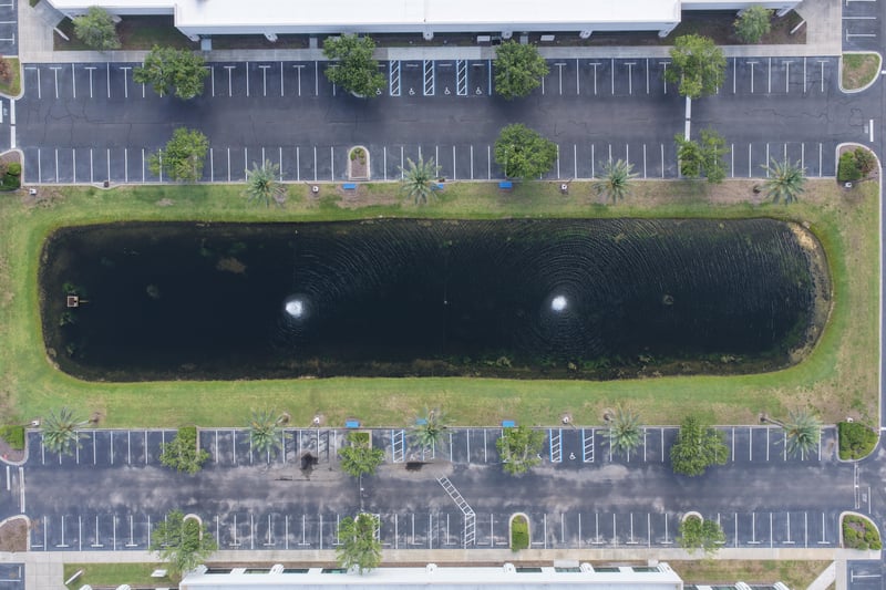Aerial view of a pond with fountain between parking lots at 10550 Deerwood Park Blvd, Jacksonville, FL 32256