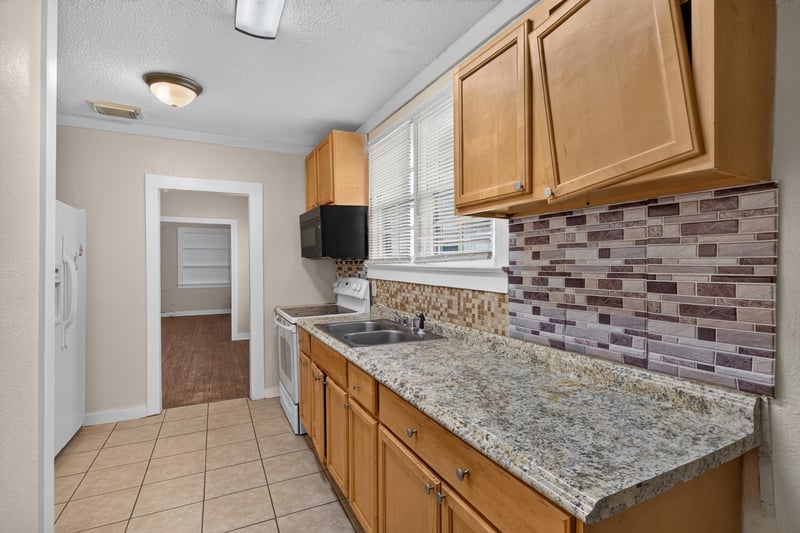 Kitchen counter with granite surface and mosaic backsplash at 1473 State St W, Jacksonville, FL 32209