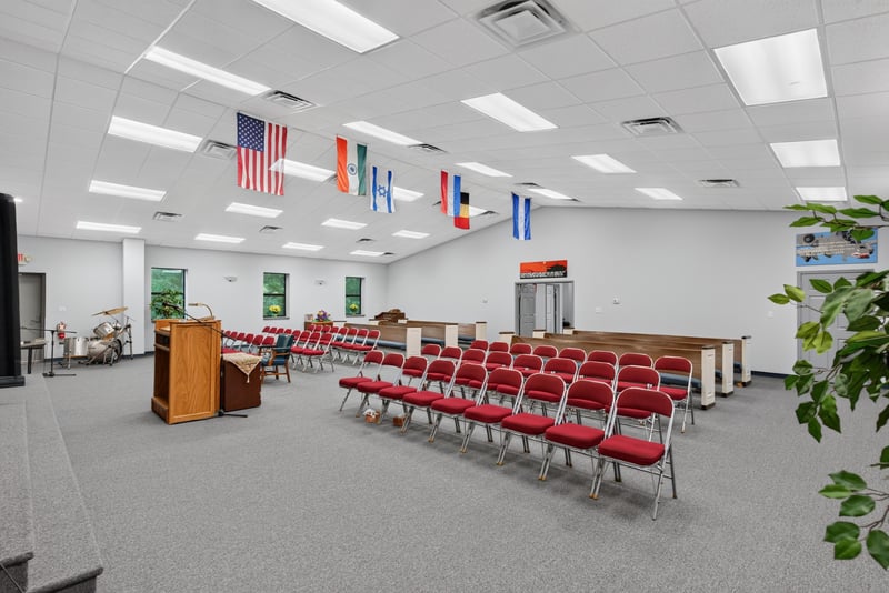 Assembly hall view toward podium with chairs and flags at 1038 County Rd 315, Melrose