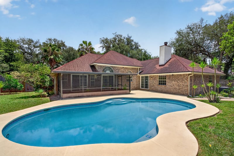 Backyard pool with brick home and chimney at 12810 Swamp Owl Ln