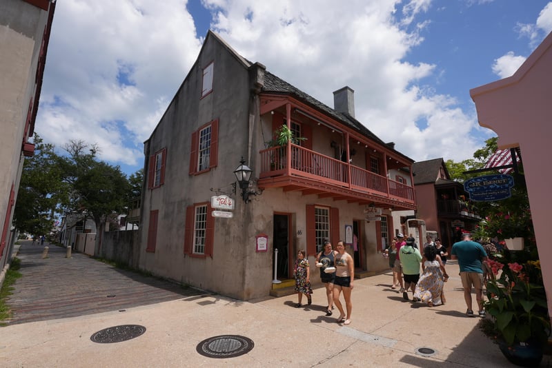 Front entrance of a historic stucco building with wrought-iron balcony and visitors on the sidewalk at 29 Cuna St, St. Augustine, FL 32084