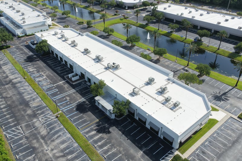 Aerial view of a building roof with parking lot and pond at 10550 Deerwood Park Blvd, Jacksonville, FL 32256
