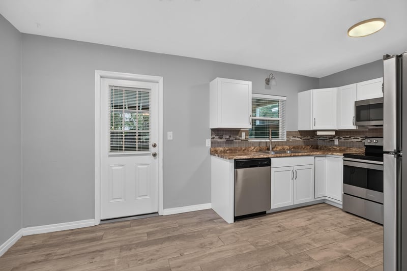 Kitchen with side door and white cabinets at 2256 Inwood Cir S, Jacksonville, FL