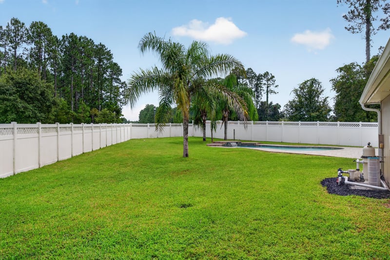 Backyard lawn with palm tree and fence at 706 Grampian Highlands Dr, St. Johns, FL 32259