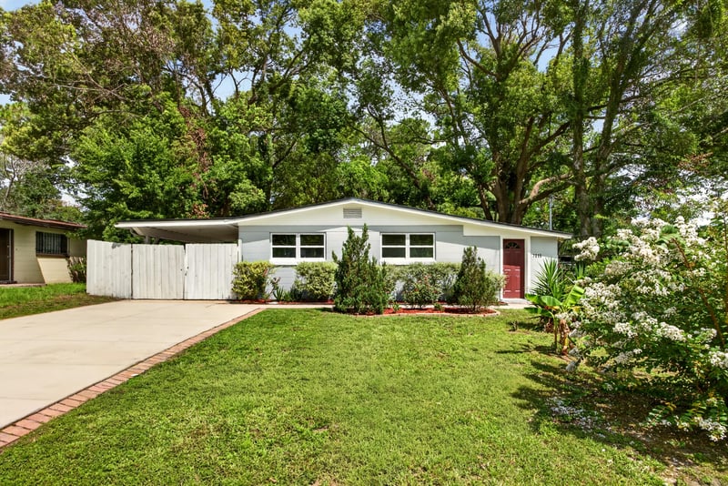 Ranch home front exterior with lawn and mature trees at 7015 Miss Muffet Ln N, Jacksonville, FL 32210