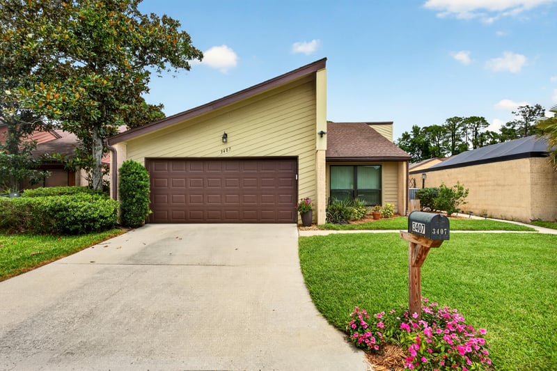 Front exterior with A-frame roofline and two-car garage at 3407 Fairbanks Grant Rd N, Jacksonville, FL 32223