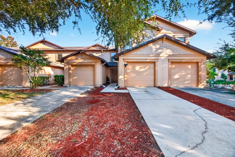 Front exterior with attached garage and tree-lined walkway at 7723 Playschool Ln, Jacksonville, FL