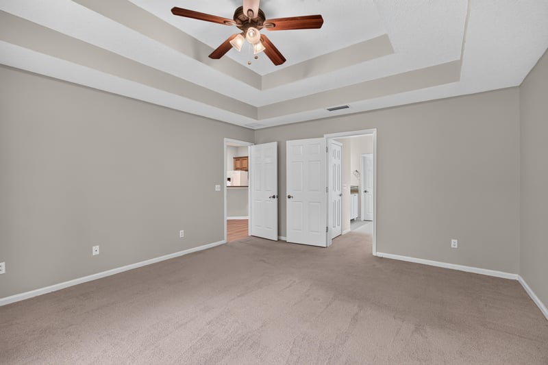 Empty bedroom with tray ceiling and double doors at 1955 GUARDED Way, Fleming Island, FL 32003