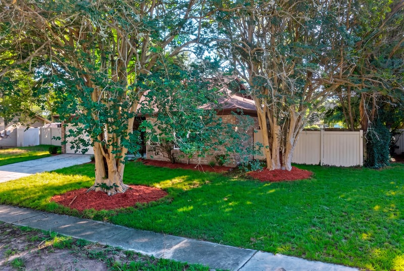 Front yard with mature trees and mulched landscaping at 8453 Boysenberry Ln W, Jacksonville, FL