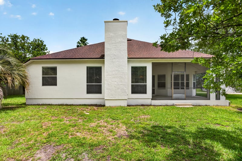 Back exterior with chimney and screened porch at 2480 Ridge Will Dr, Jacksonville, FL 32246