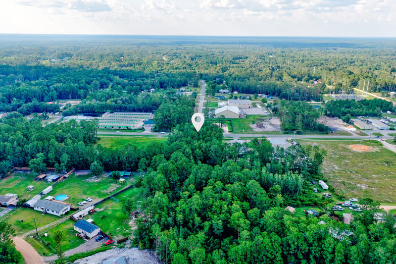 Aerial of the rural area with scattered buildings and a pond at 4393 Co Rd 218, Middleburg, FL 32068