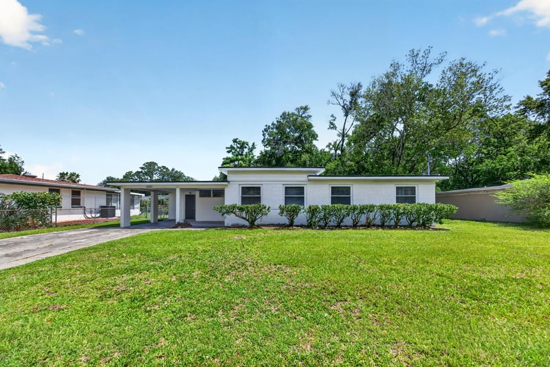 Front exterior with manicured lawn and mature trees at 6238 Randia Dr, Jacksonville, FL 32210