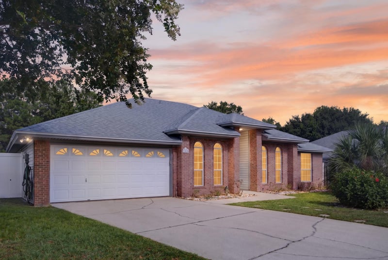 Front exterior at day-to-dusk with arched windows and three-car garage at 11828 Heather Grove Ln, Jacksonville, FL