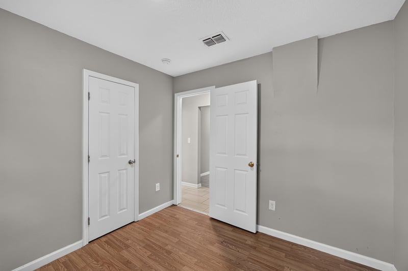 Hallway with doors and wood floor at 7015 Miss Muffet Ln N, Jacksonville, FL 32210