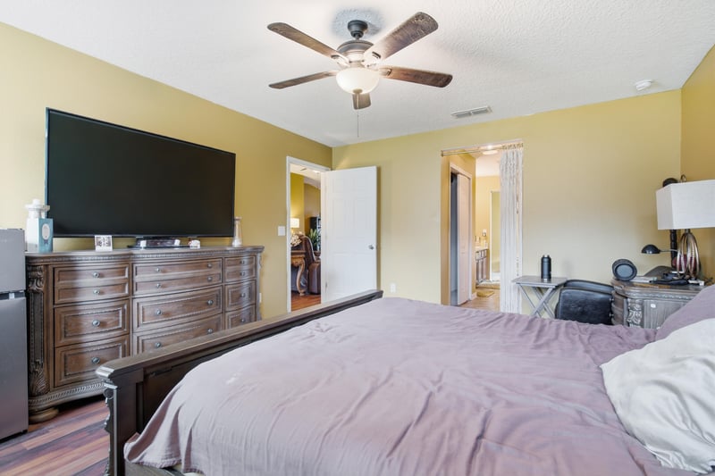 Primary bedroom with dresser and mounted TV at 7392 Timber Falls Ct
