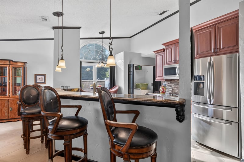Kitchen bar seating with stainless fridge at 6931 Cane Grass Ln E, Jacksonville, FL 32244