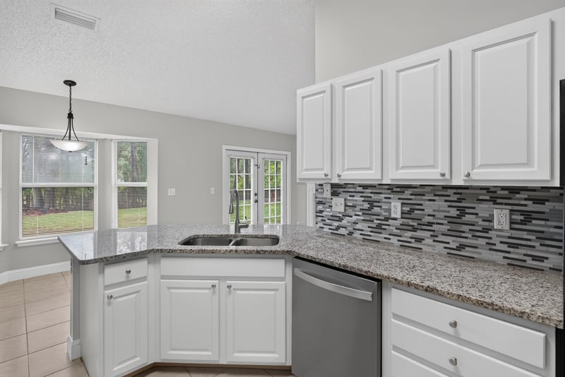 Kitchen with white cabinets and pendant light at 12949 Chets Creek Dr S, Jacksonville, FL 32224