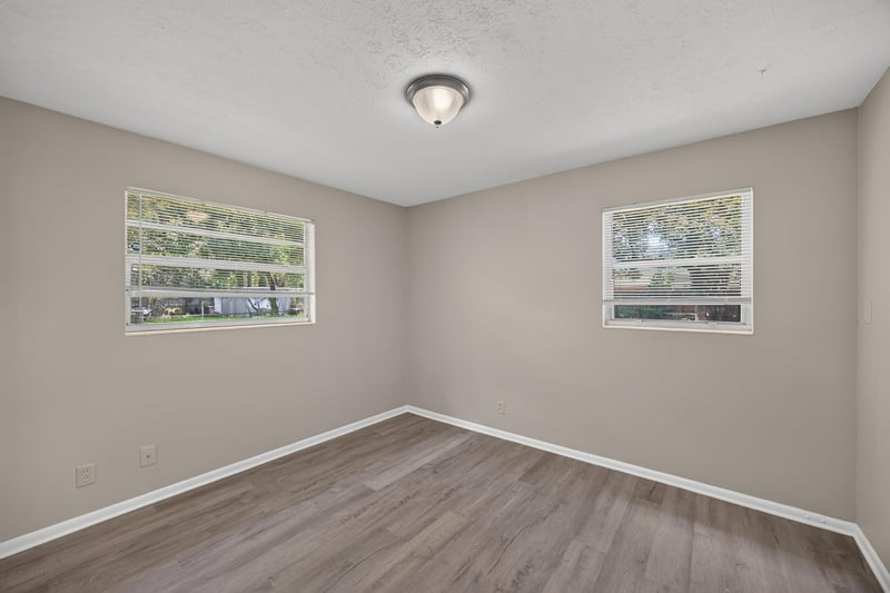 Bedroom with wood-look flooring and two windows at 5527 Beney Rd, Jacksonville, FL 32207