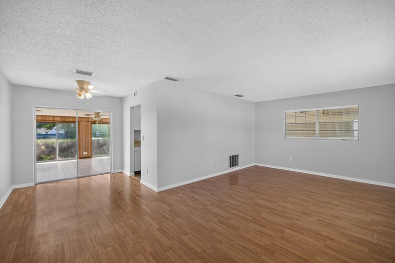 Living room with wood laminate floors and view toward kitchen at 328 Palos Ct, St. Augustine, FL