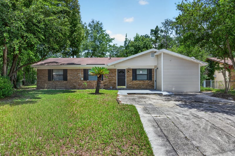 Front exterior view of brick ranch home with driveway and mature oak trees at 7453 Jade Dr N, Jacksonville, FL 32210
