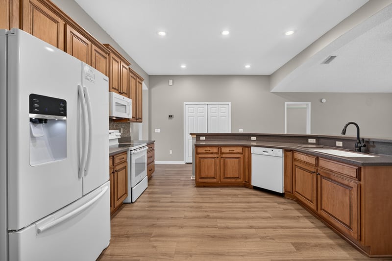 Kitchen with white appliances and wood cabinets at 1955 GUARDED Way, Fleming Island, FL 32003