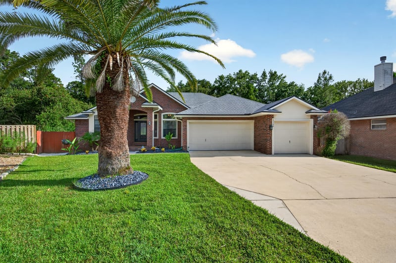 Front exterior with three-car garage at 2125 Blue Heron Cove Dr, Orange Park, FL 32003