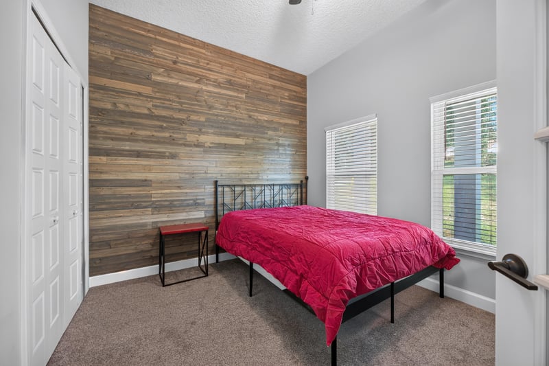 Bedroom with wood accent wall and red bedspread at 2817 Camel Cir, Middleburg, FL
