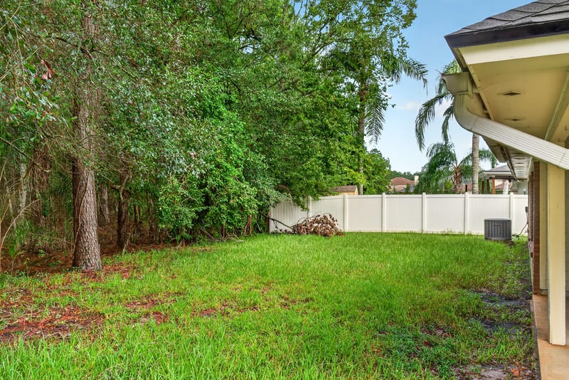 Backyard with grass and wooded tree line at 11669 Collins Creek Dr, Jacksonville, FL 32258
