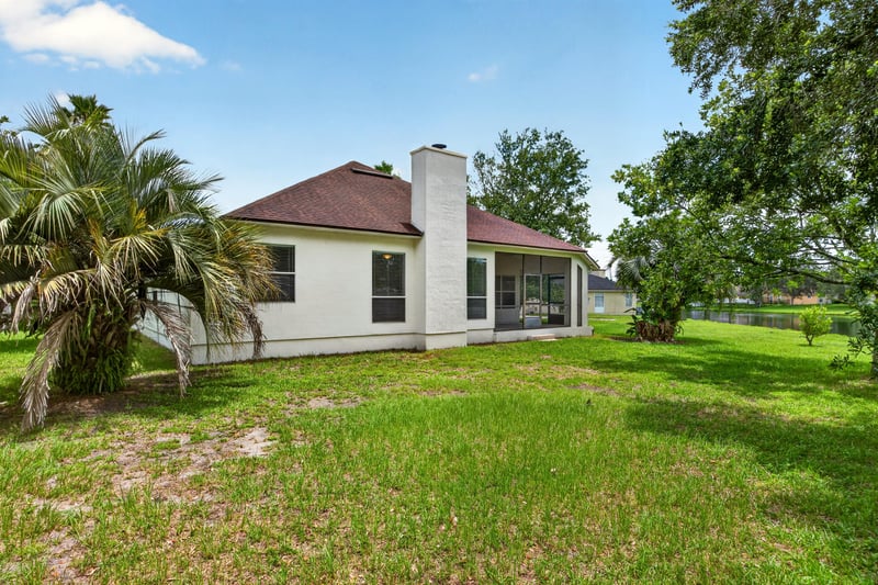 Back exterior with chimney and screened porch at 2480 Ridge Will Dr, Jacksonville, FL 32246