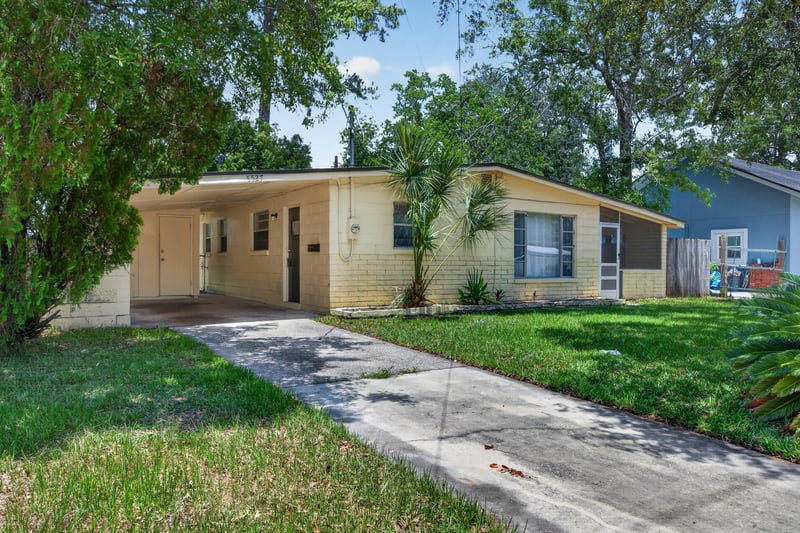 Front exterior with carport and shaded lawn at 5527 Beney Rd, Jacksonville, FL 32207