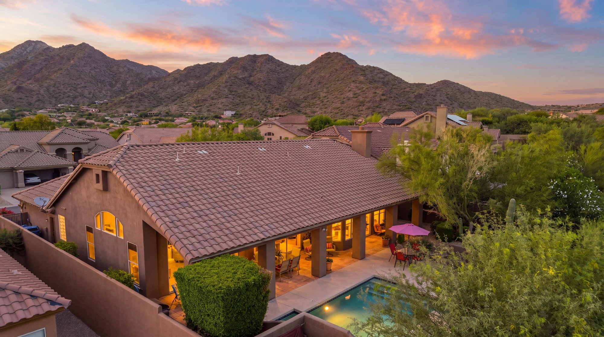 Virtual twilight aerial of a tile-roof home and pool below the mountains