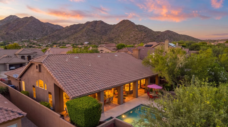 Virtual twilight aerial of a tile-roof home and pool below the mountains