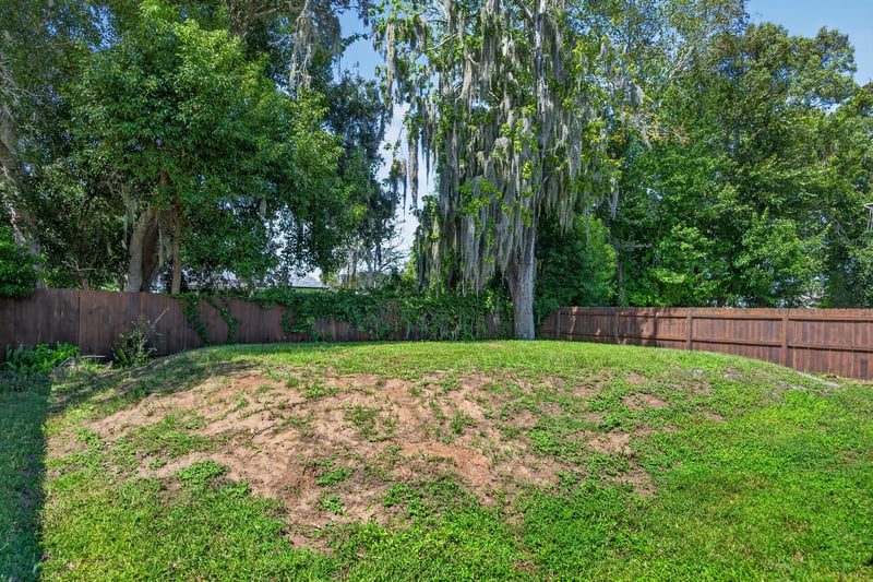 Side yard with grass, trees and wood fencing at 2855 N 8th St, St. Augustine, FL 32084