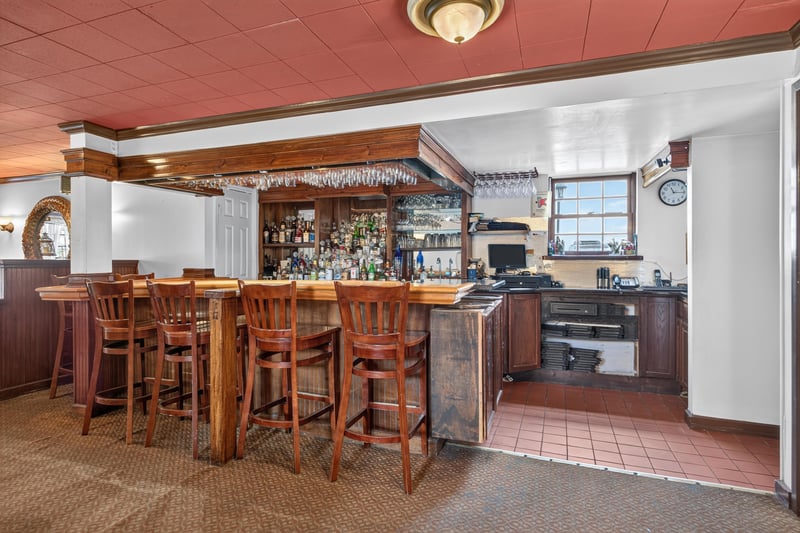 Bar area with wood stools and stocked shelves at 115 Cordova St, St. Augustine, FL