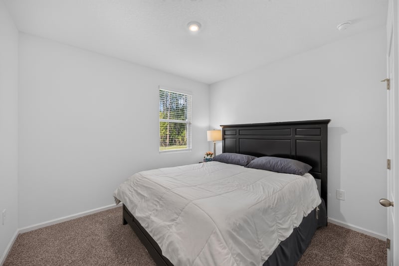 Primary bedroom with dark wood bed frame at 65255 Frst Glen Ln, Yulee, FL 32097