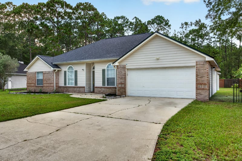 Front exterior with curved driveway and landscaping at 8921 Needlepoint Pl, Jacksonville, FL 32244