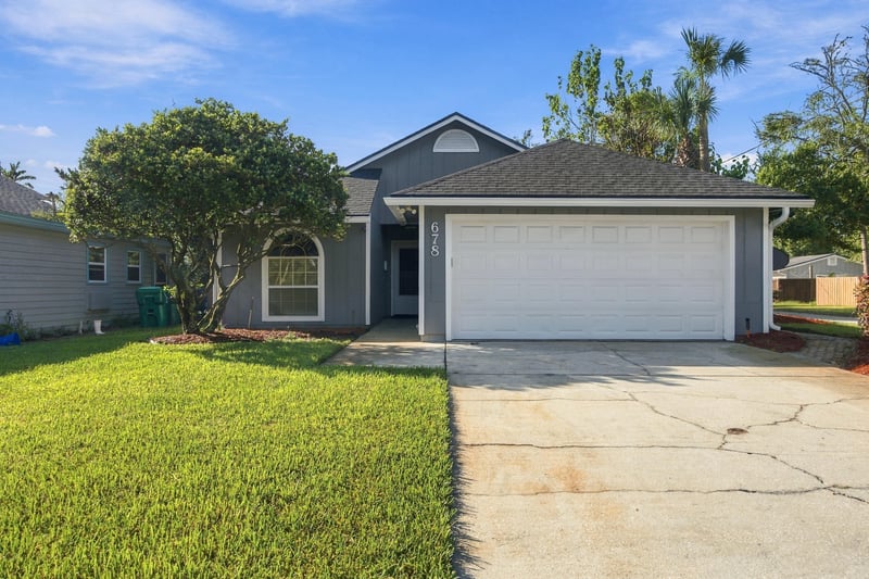 Front exterior with mature trees and lawn at 678 5th Ave N, Jacksonville Beach, FL 32250