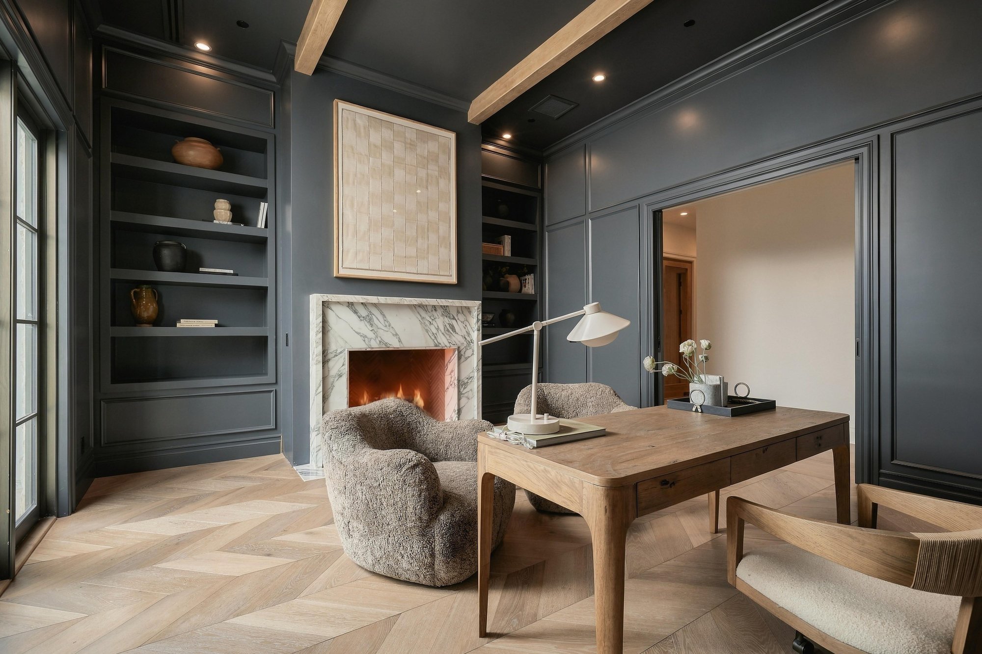 Dark-paneled office with a marble fireplace and built-in shelves