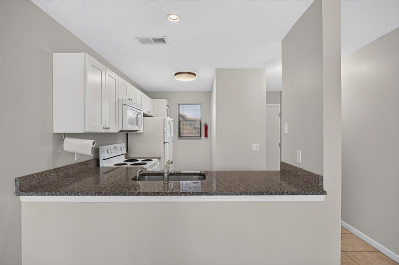 Kitchen with white cabinets and dark countertops at 700 W Pope Rd unit h61, St. Augustine, FL 32080