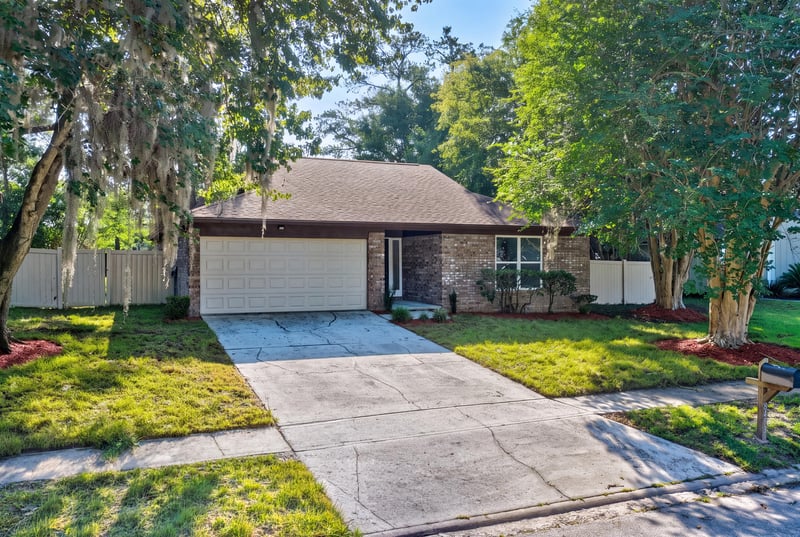 Front exterior view of brick home with driveway and landscaped lawn at 8453 Boysenberry Ln W, Jacksonville, FL