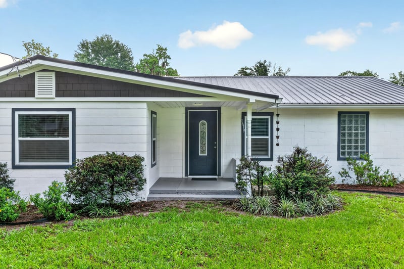 Close front exterior showing entry door and foundation plantings at 1619 Hammond Blvd, Jacksonville, FL