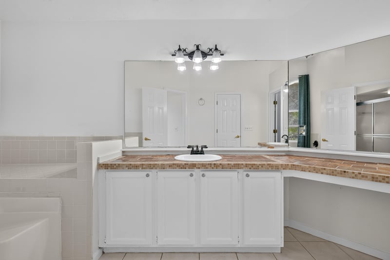 Primary bathroom dual vanity with mirror at 12810 Swamp Owl Ln