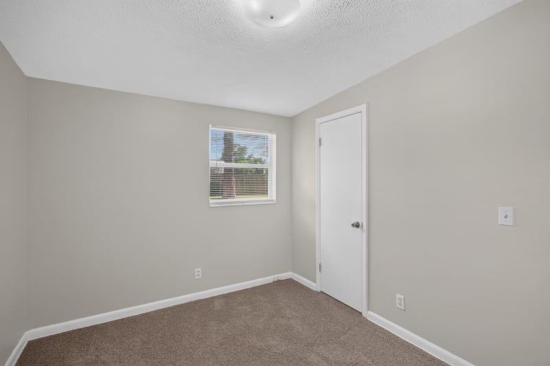 Carpeted bedroom with window and door at 87 Saratoga Cir S, Atlantic Beach, FL