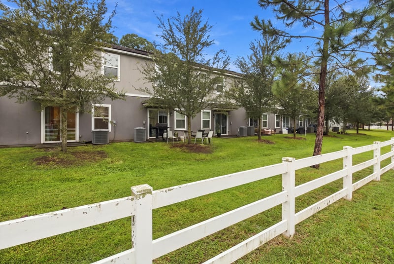 Grass area with white fence beside the townhome row in Jacksonville, FL