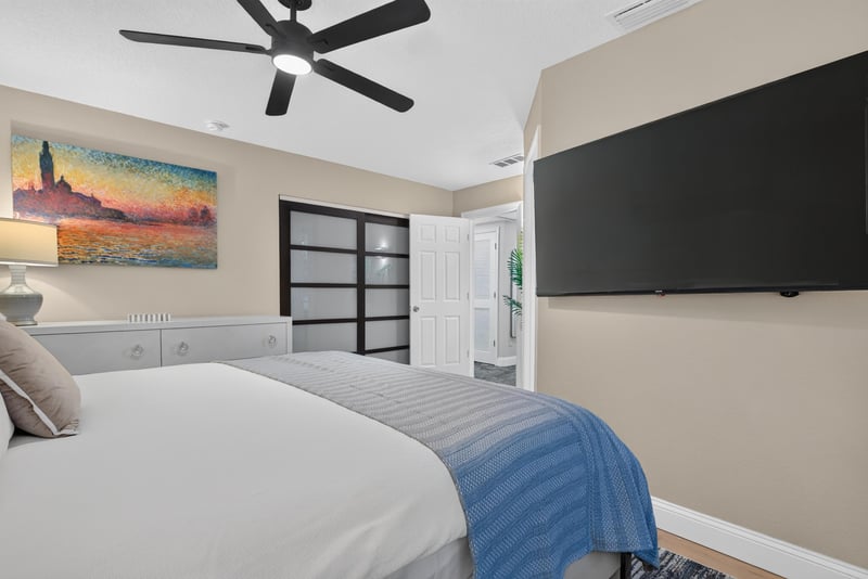 Bedroom with sliding closet doors and TV at 1525 8th St N, Jacksonville Beach, FL