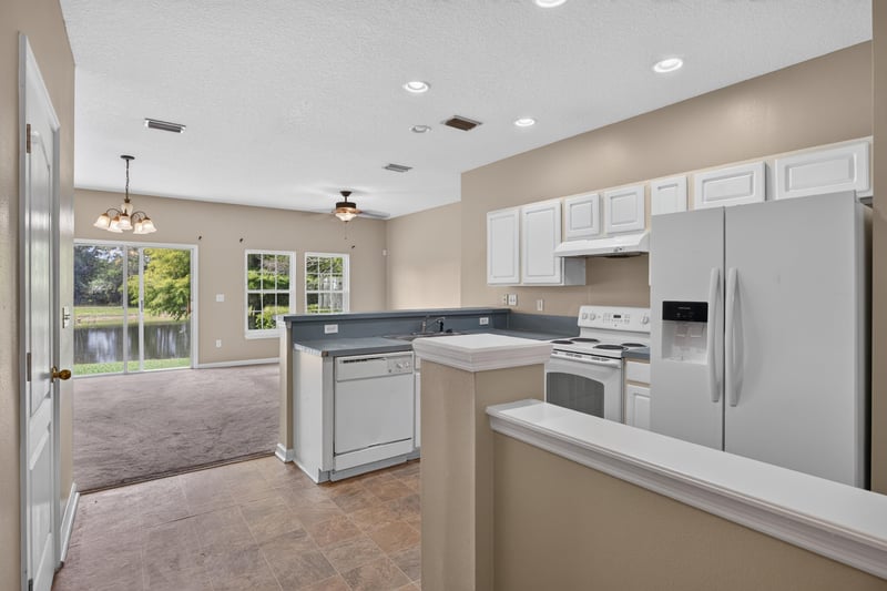 Open living area with sliding glass door and view to kitchen at 1572 Biscayne Bay Dr, Jacksonville, FL 32218