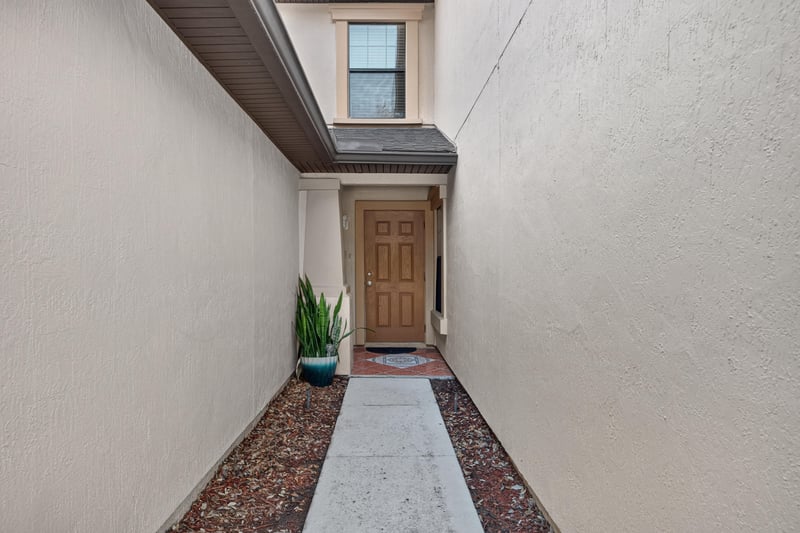 Covered front entry with wood door and tile walkway at 7723 Playschool Ln, Jacksonville, FL
