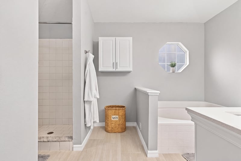 Primary bathroom tile shower and octagon window at 11197 Illford Dr