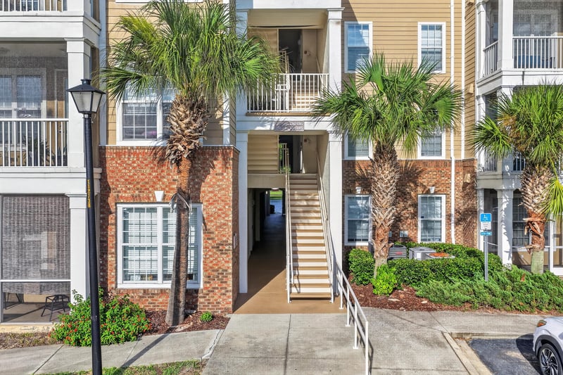 Street-level view of the condo building entrance with palm trees at 11251 Campfield Dr unit 1202, Jacksonville, FL 32256
