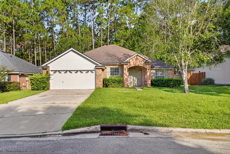 Brick one-story home with two-car garage and mature trees at 299 John's Creek Pkwy, St. Augustine, FL 32092